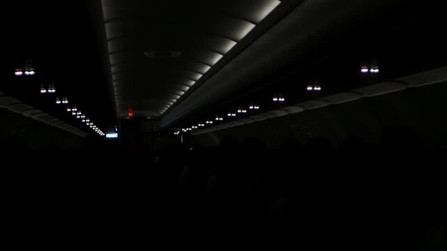 view inside airplane cabin full with passenger inside aircraft while traveling flying in night time flight while dime light down ready to landing, holiday aeroplane travel transportation
