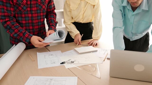 Professional engineer team discussion about house design on meeting table with architectural equipment and building blueprint scatter around at modern office. Focus on hand. Closeup. Delineation.