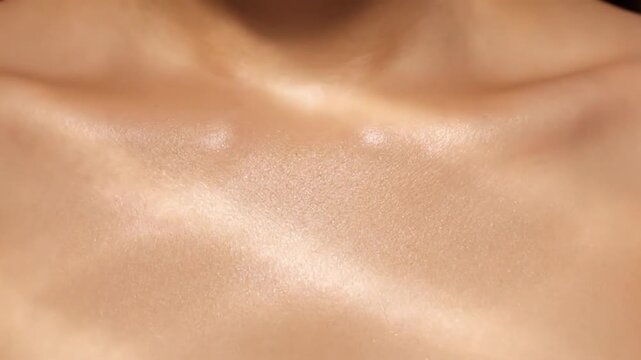 Elegant close-up video of smooth human skin texture with subtle light and shadow playing across