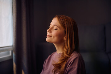 Smiling woman with eyes closed at home.