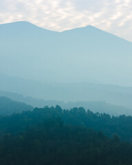 Foggy mountain range with distant peaks covered in mist, creating a soft and serene natural scene.