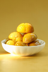Fresh Roasted Chestnuts in White Bowl on Golden Background - Autumn Seasonal Food
