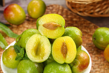 Fresh Green Xinjiang Apricots Cut in Half Showing Golden Flesh on Wicker Background Market Display