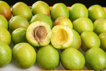 Fresh Green Xinjiang Apricots at Market Display with Cut Fruit Showing Golden Flesh and Pit