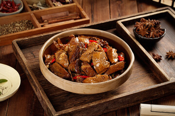 Braised Goose Meat in Iron Pot with Traditional Spices and Seasonings on Wooden Serving Tray