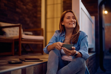 Obraz premium Happy woman day dreaming while drinking coffee on porch.