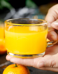 Fresh Orange Tangerine Juice in Glass Cup Held by Hands - Guangxi Honey Citrus Drink