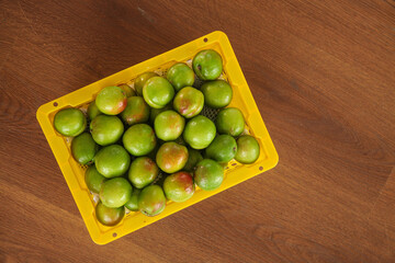 Fresh Green Plums in Yellow Container on Wooden Table - Healthy Organic Fruit Display