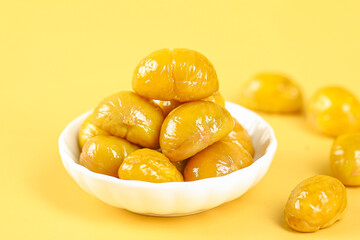 Fresh Roasted Chestnuts in White Bowl on Yellow Background - Golden Glazed Nuts