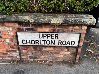 Street sign for Upper Chorlton Road in Manchester, UK, with brick background