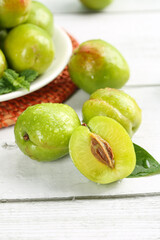 Fresh Green Plums from Xinjiang with Smooth Skin on Rustic White Wood Background