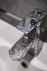A dirty metal faucet in the sink with limescale, rust marks, and grime around the mixer, showing neglect and the need for cleaning.