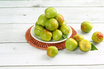 Fresh Green Xinjiang Apricots in Bowl on White Wooden Background - Elegant Fruit Display