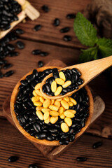 Heart-shaped bowl of black and yellow beans with wooden spoon on rustic table