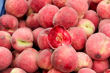 Fresh Stacked Peaches at Market Display with Cut Peach Showing Pit