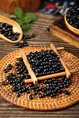 Black beans in wooden container on wicker basket with spoons - healthy legume cooking ingredient