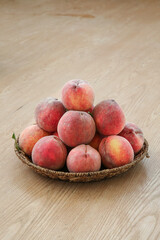 Freshly Picked Red Blood Peaches from Hubei in Wicker Basket on Wood Table