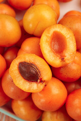 Fresh Xinjiang Apricots Beautifully Displayed in Wooden Bowl with Cut Halves Showing Orange Flesh and Pits