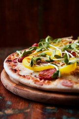 Pizza with chorizo ​​sausage, mozzarella cheese and yellow pepper. Rustic wooden background. Soft focus.	