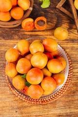Fresh Xinjiang Apricots in Glass Bowl on Rustic Wooden Table with Wicker Baskets