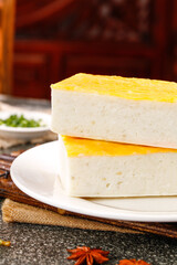 Jingzhou Fish Cake Traditional Chinese Specialty Layered Dessert with Golden Egg Topping on White Plate