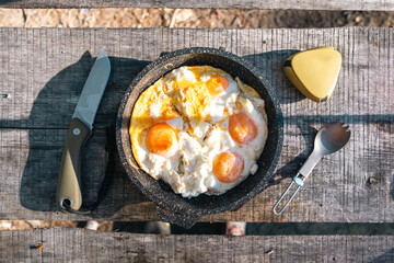 Food on a hike frying pan on a fire with chicken eggs