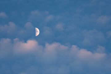 Moon and clouds in the sky at sunset
