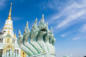 Naga serpent statue with a backdrop of a temple under a bright blue sky in Wat Saensuk Suthi Wararam