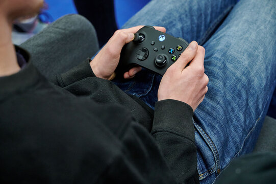 A person intensely gripping an Xbox controller, engaged in gameplay at Carrefour Gaming Days event in Warsaw, 2022. The atmosphere is focused and competitive.