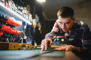 Working process of the leather belt in the leather workshop. Man holding crafting tool and working