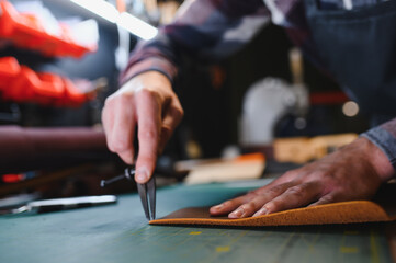 Tailor cobbler hold different rolls natural brown leather, working with textile in workshop