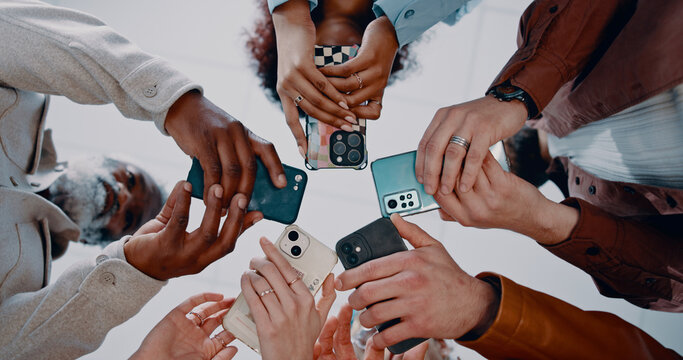 Business people, hands and below with phone in circle for data sync, share or communication in office. Low angle, group or employees with mobile smartphone for networking or connectivity together