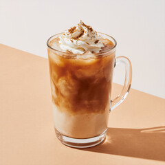 Iced pumpkin spice latte with whipped cream on a warm pumpkin background, clean eye-level studio shot with a soft halo shadow