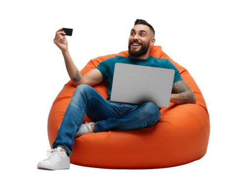 Joyful man utilizing a laptop and credit card while sitting in a vibrant orange beanbag chair