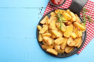 Tasty baked potatoes with rosemary on light blue wooden table, flat lay. Space for text