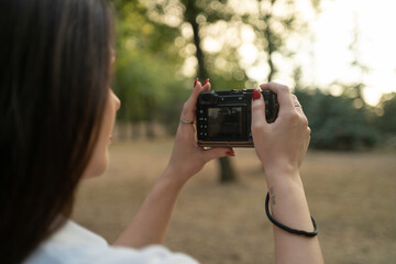 A woman hands holding a compact digital camera and taking photos in nature