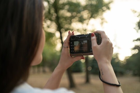 A woman hands holding a compact digital camera and taking photos in nature