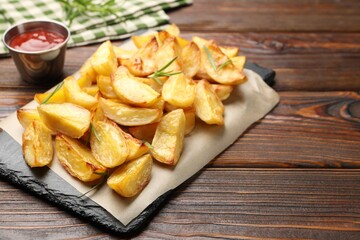 Tasty baked potatoes with rosemary on wooden table, closeup