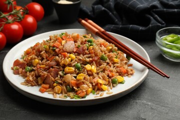 Delicious fried rice with vegetables and bacon served on grey table, closeup
