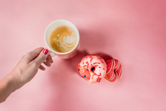 Hand Holding Coffee with Donuts on Pink Background