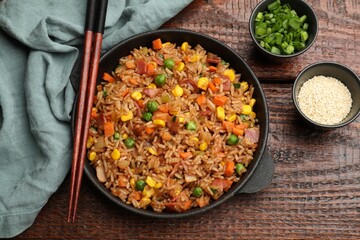 Delicious fried rice in baking dish served on wooden table, flat lay