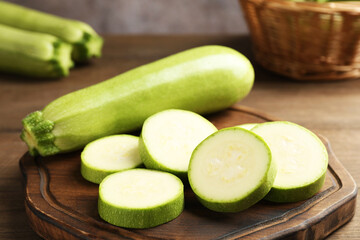 Fresh ripe zucchinis on wooden table, closeup. Whole and cut