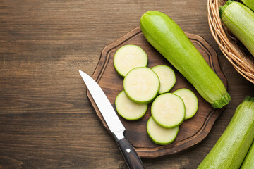 Fresh ripe zucchinis and knife on wooden table, flat lay. Space for text