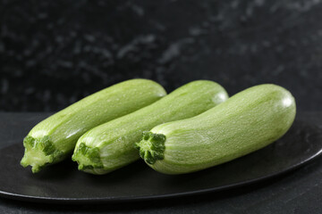 Fresh ripe zucchinis on black table, closeup