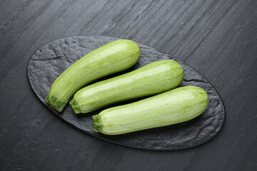 Fresh ripe zucchinis on black textured table, top view