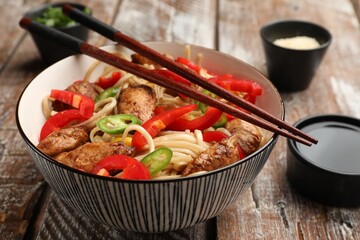 Delicious noodles with meat and vegetables served on wooden table, closeup