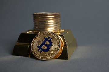 Bitcoins and gold bars on grey background, closeup