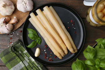 Pickled asparagus and spices on wooden table, flat lay