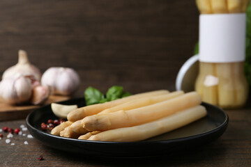 Pickled asparagus and spices on wooden table, closeup
