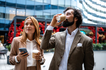 Businesspeople drinking coffee and using smartphone outdoors
